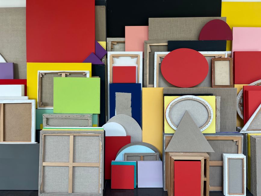 A vibrant arrangement of multicolored geometric canvases creating a lively abstract art piece.
