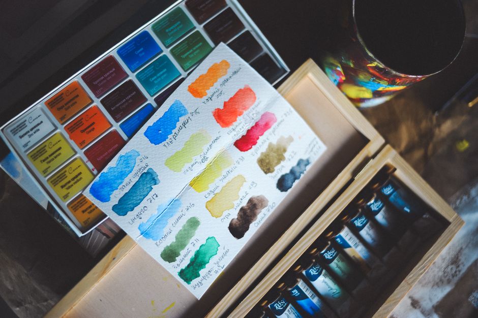 Vibrant watercolor palette with various paint swatches on textured paper.