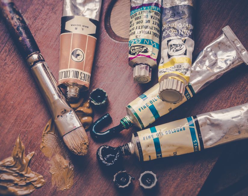 Close-up of oil paint tubes and brushes on a wooden surface, perfect for creative projects.